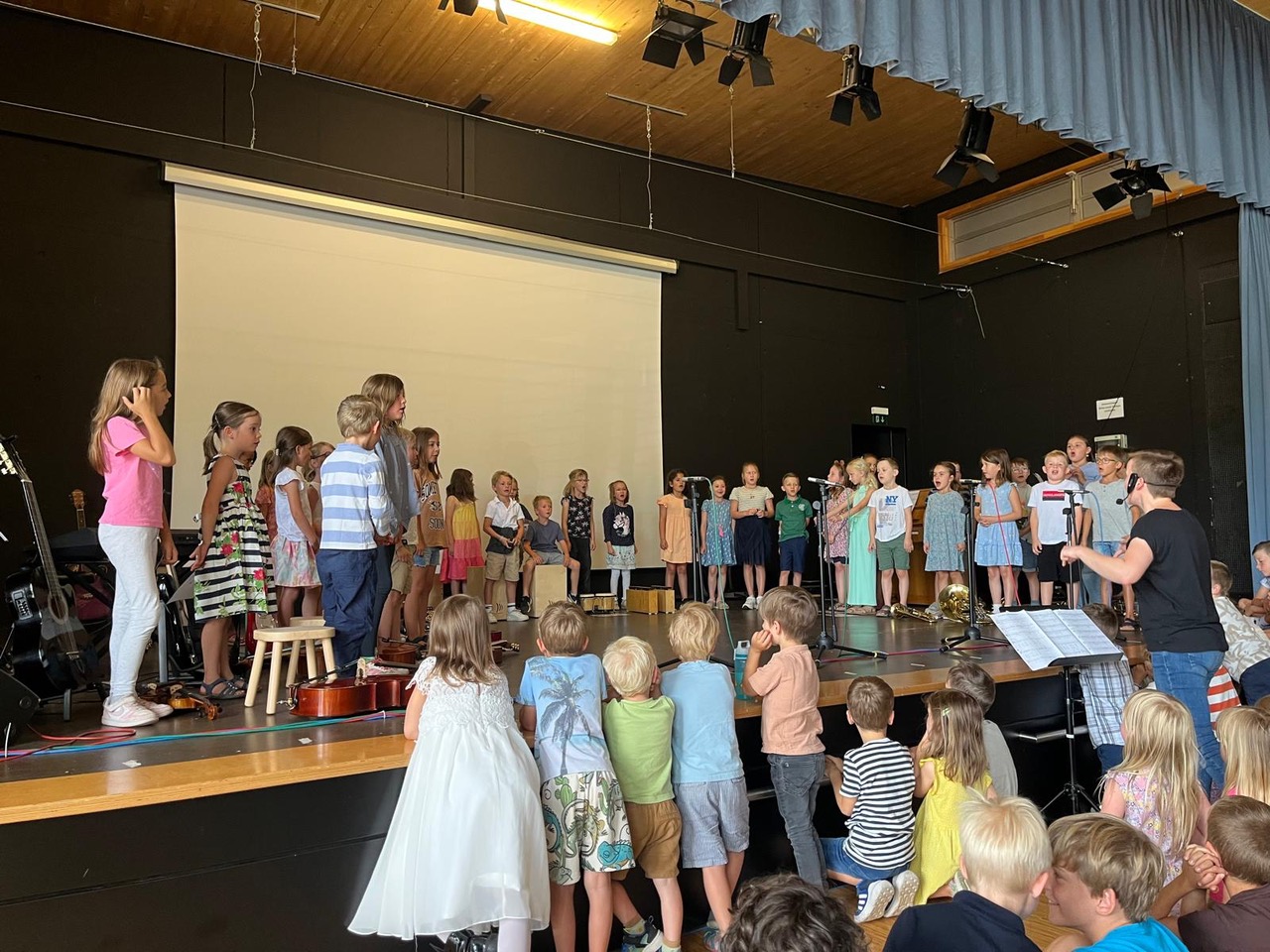 Eine große Gruppe Kinder singt und musiziert auf der Bühne.