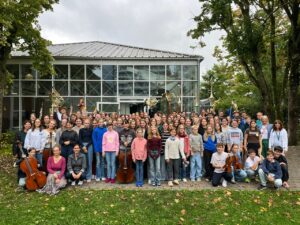 Die Musikerinnen und Musiker der Orchester der Musik- und Kunstschule Achern Oberkirch auf einer Wiese vor dem Humboldt Institut in Bad Schussenried.