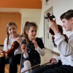 Drei Kinder probieren Geigen aus